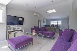 sala de estar con sofás morados y TV en Swan Lake View House, en Berrara