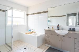 Un baño blanco con bañera y lavabo. en Swan Lake View House, en Berrara 26 fotos más