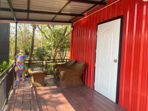 a red building with chairs and a white door at แอนฟาร์มรีสอร์ทแอนด์คาเฟ่ลำปาง in Mae Mo