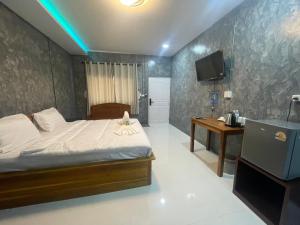 a bedroom with a bed and a desk and a television at J House Has Love in Sukhothai