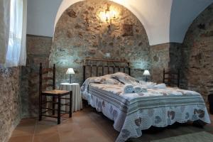 1 dormitorio con cama y pared de piedra en Apartamentos Rurales La Casa de Luis en Santa Cruz de la Sierra