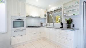 a white kitchen with white cabinets and a sink at Halcyon in Kiama