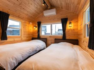 Duas camas num quarto com paredes e janelas de madeira em Myoko Onsen cottage Ajisai em Myoko