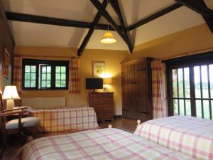 a bedroom with two beds and a tv and windows at Combe Lancey Farmhouse B&B in Crediton