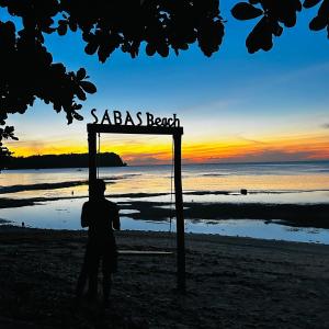 a person standing under a sign on a beach at Sabas Beach and Campsite in Siquijor