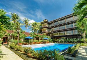 a hotel with a swimming pool and palm trees at Qualia Resort Phu Quoc in Phú Quốc