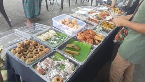 a table filled with trays of different types of food at Homestay Murah Lahad Datu in Lahad Datu