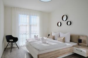 a white bedroom with a large bed and a chair at Apartment C13 mit Balkon & Nutzung der Wellness- & Aktivbereiche im "Pine Hill Resort" in Zirchow