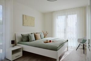 a white bedroom with a bed with a tray on it at Apartment C13 mit Balkon & Nutzung der Wellness- & Aktivbereiche im "Pine Hill Resort" in Zirchow
