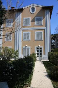żółty budynek z białym przycinaniem i chodnikiem w obiekcie Ceccarini Suite w mieście Riccione