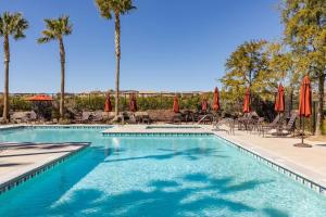 una piscina con sombrillas, sillas y palmeras en GOODE HOMES Luxury Villa with Community Pool and Spa, en Santa Clarita