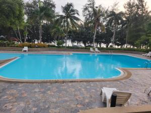 a large blue swimming pool with chairs and palm trees at VIP 375 large studio, ocean view in Rayong