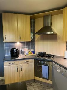 eine Küche mit Holzschränken und einem Herd mit Backofen in der Unterkunft 3 bed Professional Suite for Long term in Aberdeen