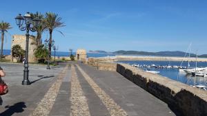 a walkway next to a harbor with boats in the water at Appartamento Parco Tarragona in Alghero