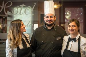 un hombre y dos mujeres parados al lado de un chef en Hotel San Paolo, en Camposampiero