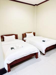 two beds in a room with white sheets at Happy Hotel in Vang Vieng