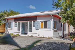 a small white house with blue shutters at Le Jardin d'Amina in Saint-Paul