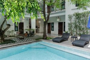 a pool in the courtyard of a building with chairs and trees at Paraiso Hotel Chiangmai in Chiang Mai