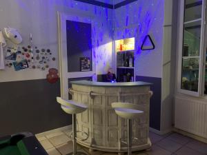 a bar with two stools in a room with purple lighting at Grande chambre familliale pour 4 à 5 personnes in Chef-Boutonne