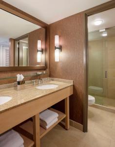 a bathroom with two sinks and a toilet and a mirror at Hyatt Lodge Oak Brook Chicago in Oak Brook