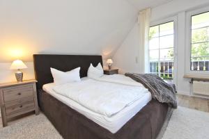 sypialnia z dużym łóżkiem z białą pościelą i poduszkami w obiekcie Ferienhaus Ostseerausch w mieście Scharbeutz
