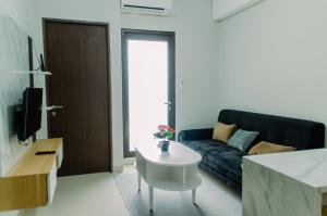 a living room with a couch and a table at Simply and Comfort Living 2BR at Transpark Bintaro Apartment By Travelio in Tangerang
