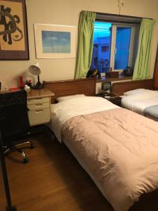 een slaapkamer met twee bedden, een bureau en een raam bij Guest House Chara in Hirosaki