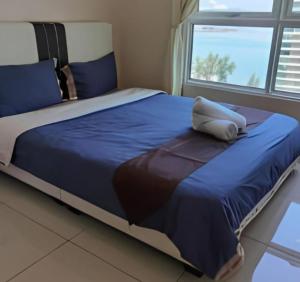 a large bed with a blue comforter and a window at Mansion One Luxurious Seaview Vacation Homes in George Town