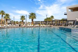 a large swimming pool with chairs and palm trees at Desert Azul townhouse in St. George