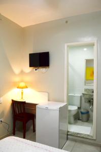 a bathroom with a toilet and a desk with a lamp at Hotel São José in São Fidélis +38 photos