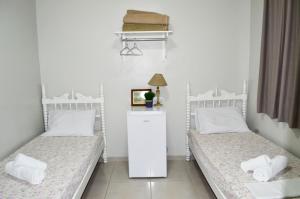 two twin beds in a room with a lamp at Hotel São José in São Fidélis