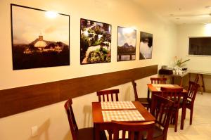 a restaurant with tables and chairs and pictures on the wall at Hotel São José in São Fidélis