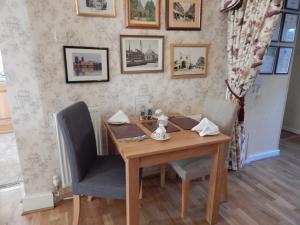a dining room table with two chairs and pictures on the wall at Fairlight Lodge in Kings Lynn +44 photos