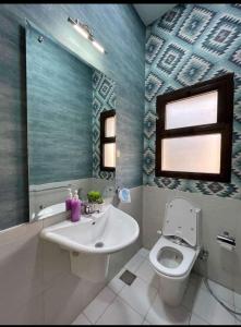 a bathroom with a sink and a toilet and a mirror at كمبوند مفيدا in New cairo