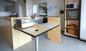 eine Küche mit einem Tisch und einer Mikrowelle in der Unterkunft Montana Backpackers Cape Town in Cape Town