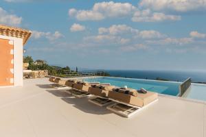a row of lounge chairs sitting on top of a swimming pool at Archontiko Stoufi, an Authentic SeaView Retreat, By ThinkVilla in Skinária