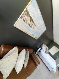 a living room with a leather couch and a painting at Pebble Beach Resort Apartment in Umhlanga +12 photos