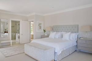 a white bedroom with a large white bed and a stool at Farm Lorraine The Loft Cottage in Franschhoek