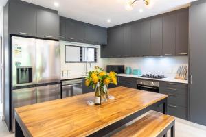 una cocina con una mesa de madera con flores en un jarrón en Sunbird - Walk To Beach - In Town - Fast Wifi, en Wilderness