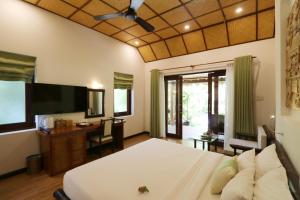 a bedroom with a bed and a desk and a television at Bamboo Village Beach Resort & Spa in Mui Ne