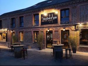 a brick building with tables and chairs in front of it at L’Auberge de papa in Auzouville-sur-Ry