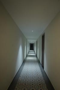 a long corridor with a white wall and a white floor at OVEL Hotel & RESORT in Ludhiana