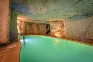 a swimming pool in a cave with a stone wall at Logis Hotel Demeure de la Vignole in Turquant