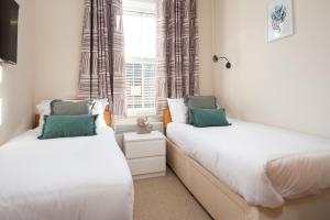 two beds in a room with a window at Harbour Heights by Coast & Country Stays in Seahouses