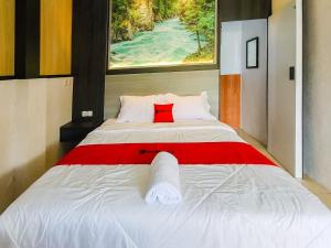 a large white bed with a red pillow on it at RedDoorz near Stasiun Banyuwangi Kota in Glagah