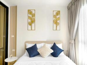 a bedroom with a bed with blue and white pillows at DCondo Reef Kathu, Phuket in Kathu