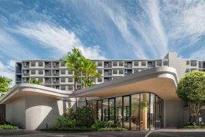 a large white building with palm trees in front of it at DCondo Reef Kathu, Phuket in Kathu