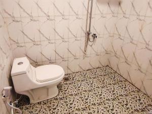 a bathroom with a toilet in a tiled wall at RedDoorz near Stasiun Banyuwangi Kota in Glagah
