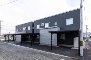 a black building with two parking spaces in front of it at Snow House LANKA in Furano