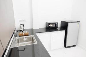 a kitchen with a sink and a black refrigerator at Baan Patupjai in Ban Pak Sa
